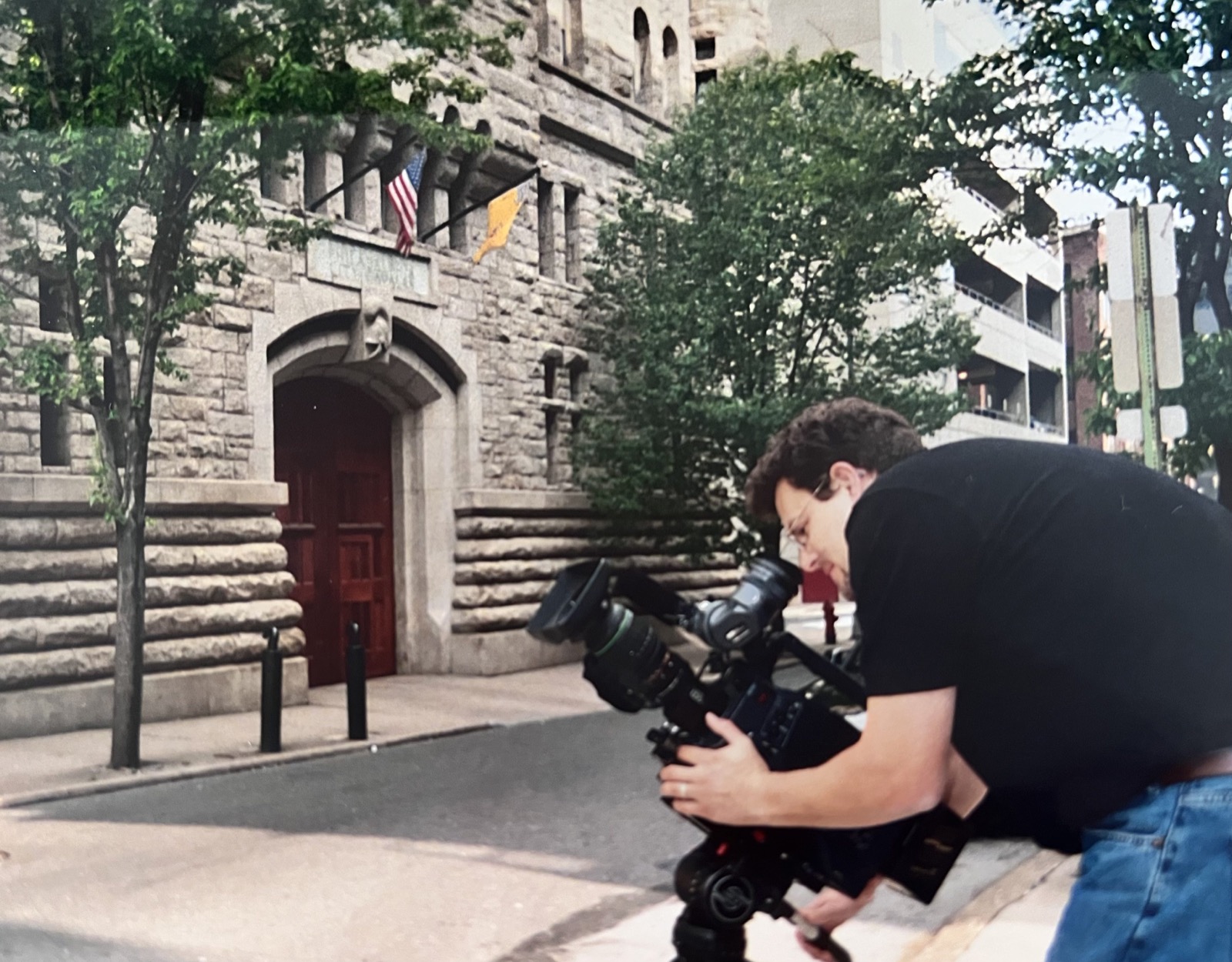 A cinematographer filming on location outside a historic stone building